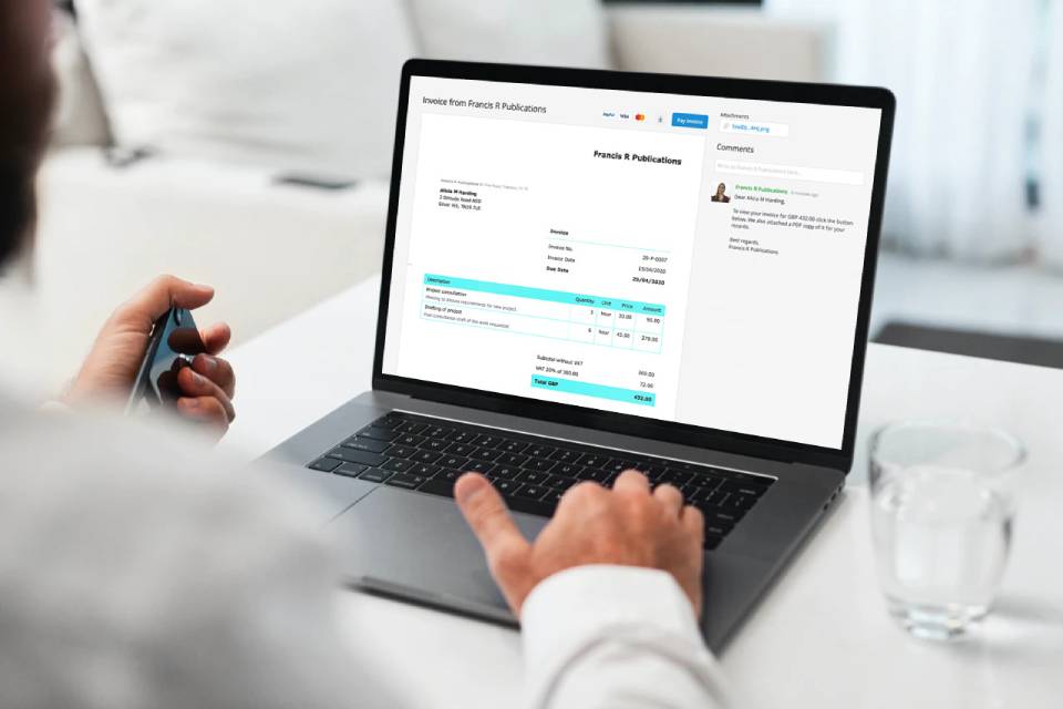 Man sitting in front of his computer looking at an invoice sent from Debitoor invoicing software with an online payment option