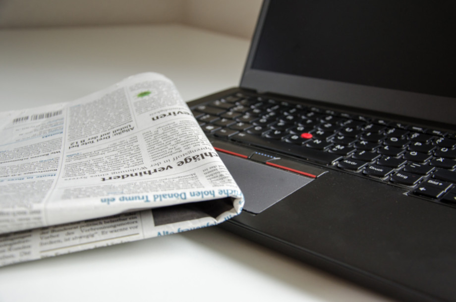 Freelance journalism invoicing templates- photo of a newspaper next to a laptop on desk