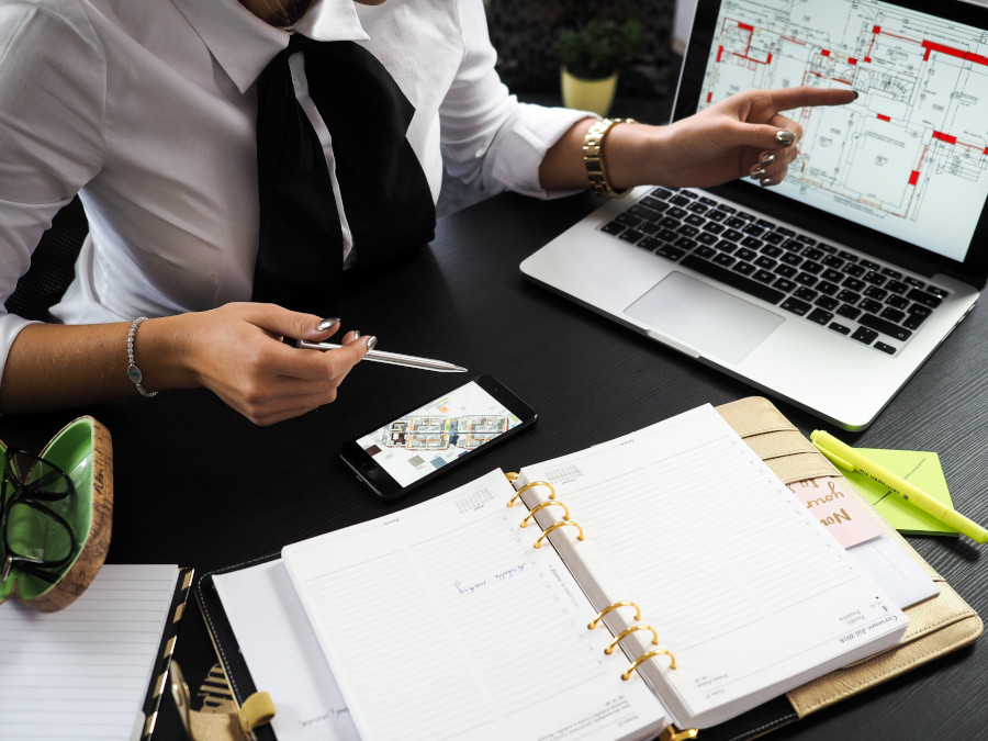 picture of woman sittaing at desk with house floor plan as real estate agent