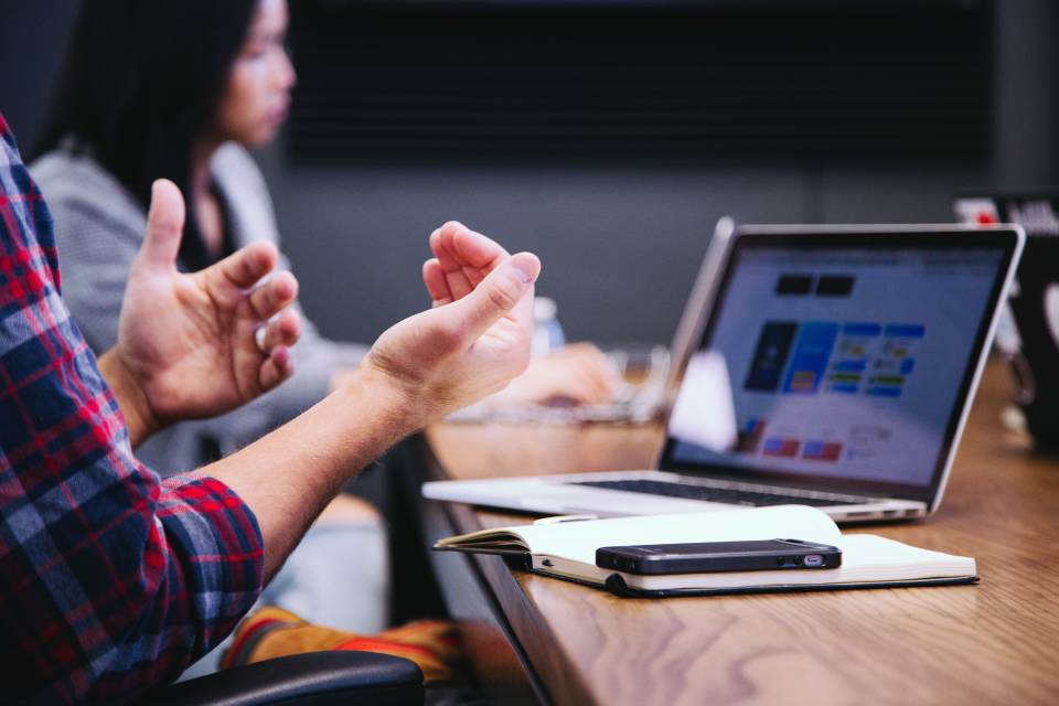 A man gesturing towards himself, maybe in a discussion about his compensation as an employee