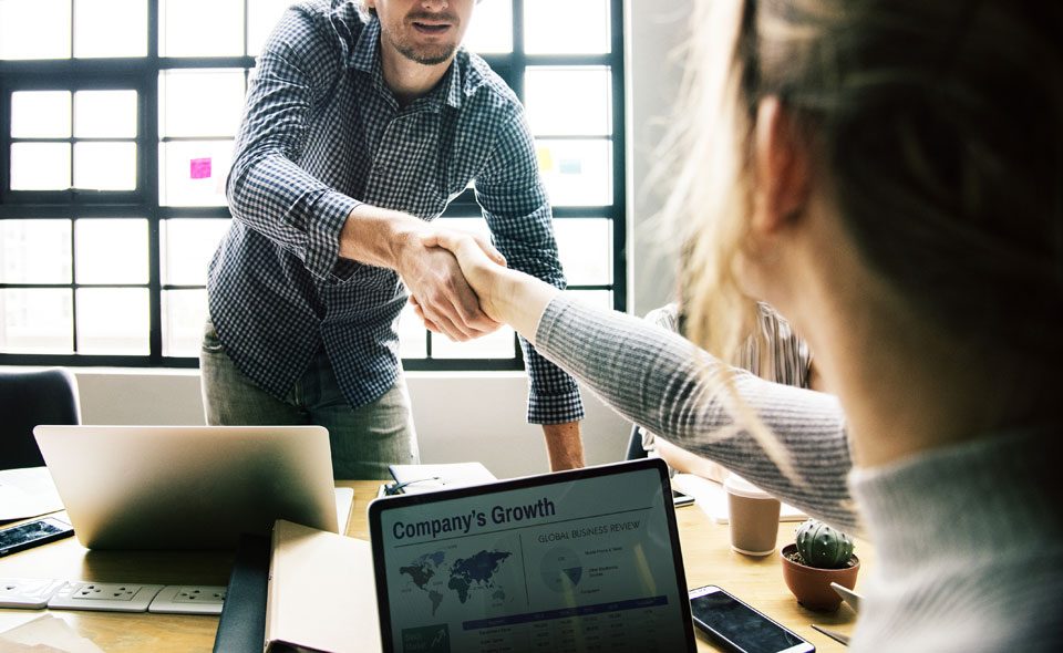 Maintaining good relationships with customers, like this man and woman shaking hands over a computer is good advice for your marketing