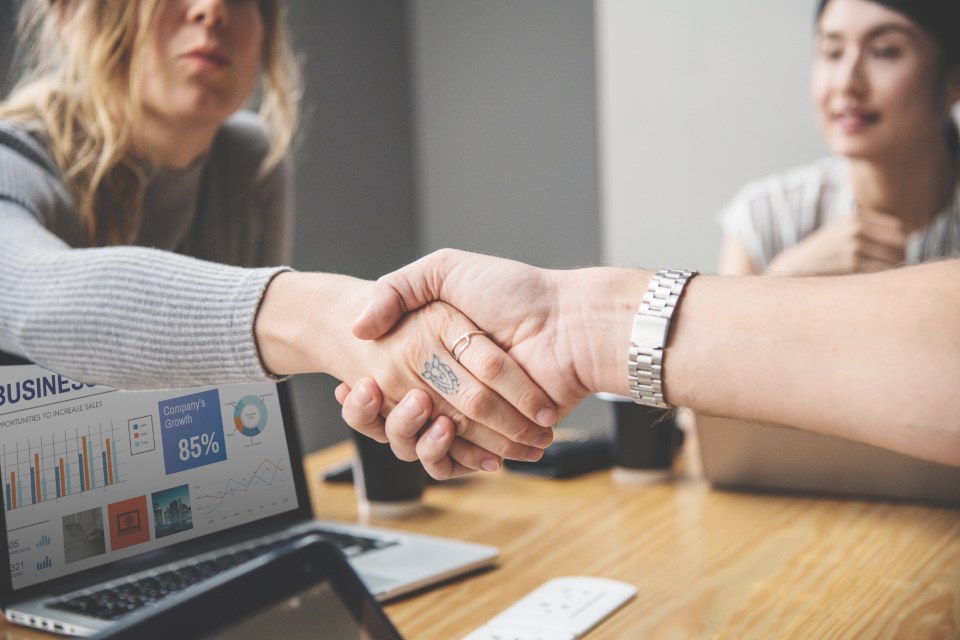 Two small business owners shaking hands while looking at a business plan