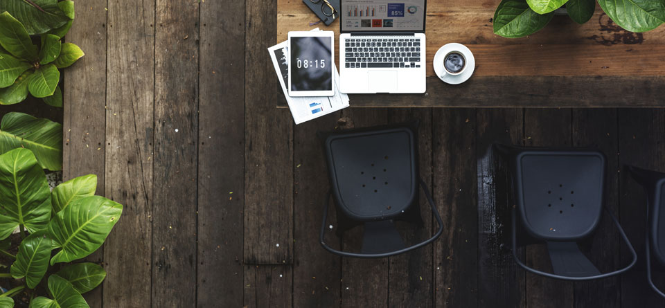 Businesses are moving towards digitisation, with ipads and laptops like these two on a wooden table with plants around.