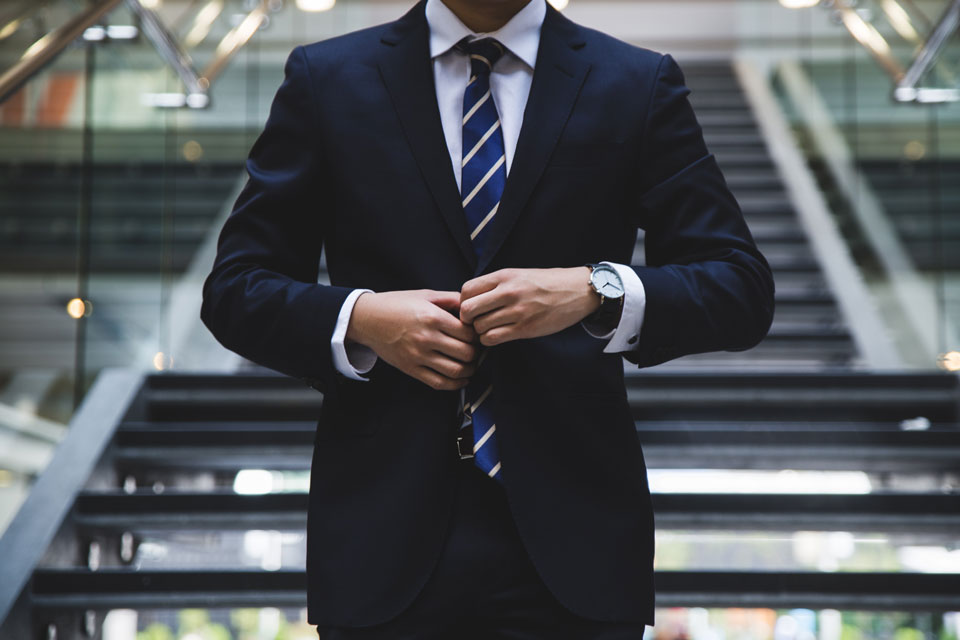 Man in a suit and tie standing in front of a building - potentially a bank